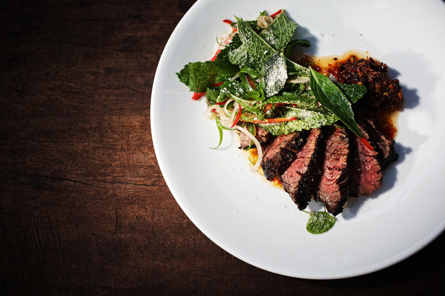 Beautifully plated Vermont steak with fresh greens and seasonal sauce